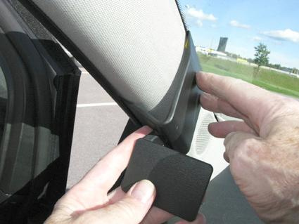 En hand pekar på en del av en bils interiör, troligtvis en Opel Meriva.