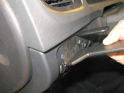 En hand som trycker på en knapp i en bilinteriör.