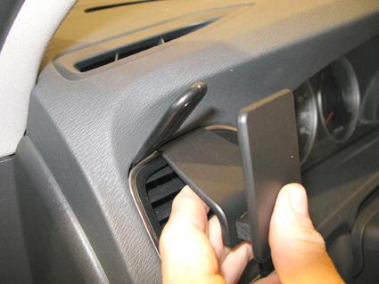 En hand håller i en montagekategori för ventilationsgaller i en bil.