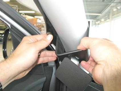 En person fäster en del vid bilens A-stolpe.