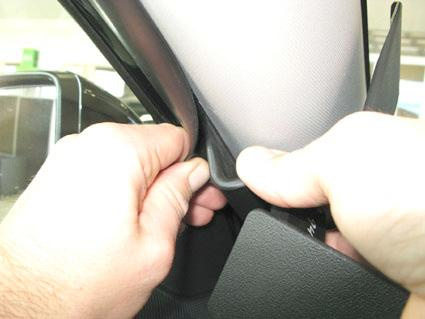 Två händer som greppar en bilinteriör, troligtvis A-stolpen på en Kia Sportage.