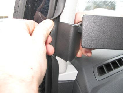 En hand justerar en del av en bilinteriör, troligtvis en spegel eller panel.