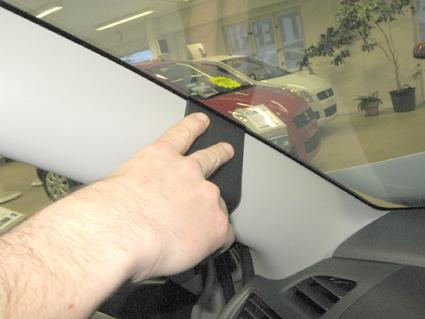 En hand trycker på en panel vid vindrutan i en Suzuki Swift.