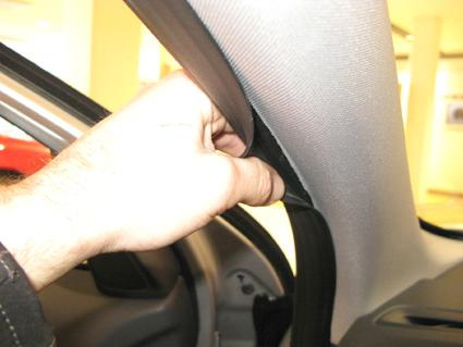 Hand som håller i en inredningsdetalj vid bilens takstolpe.