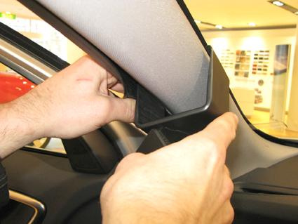 En person installerar en plastdetalj i en Volvo S60.