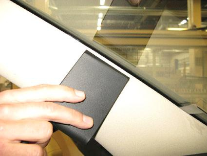 En hand håller i en svart del som ska monteras på Skoda Superb.