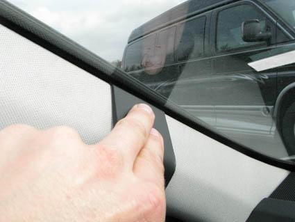 Del av bilinteriör med hand som pekar på en panel.