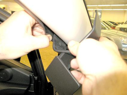 En person tar bort en klämma från bilens takbeklädnad.