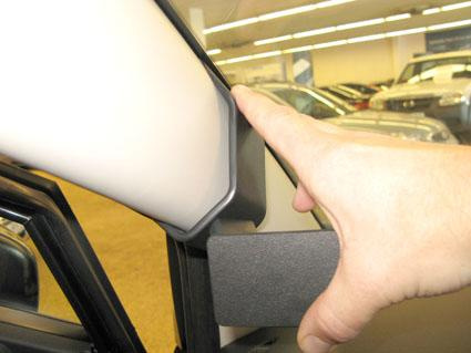 En hand pekar på en del av en bils inredning vid vindrutan.