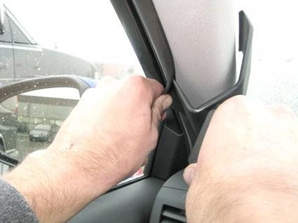 Två händer som justerar en inredningsdetalj i en bil.