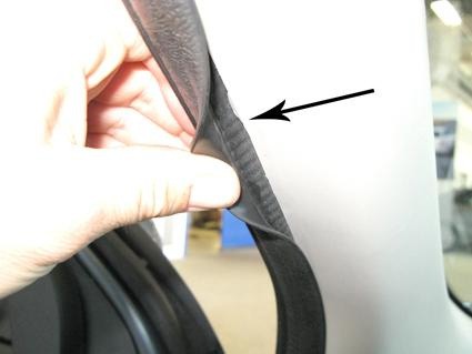 En hand som lyfter på en tätning nära en dörrpost i en Nissan Micra.