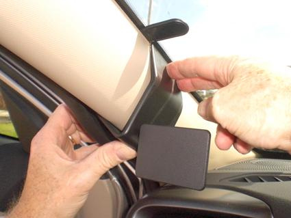 En hand fäster en komponent vid bilens A-stöd.