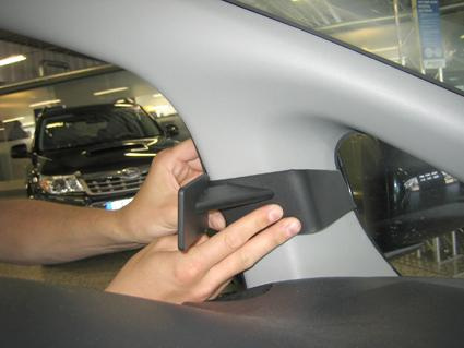 En person fäster en del i bilen, troligen en interiörkomponent.