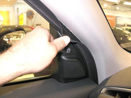 En hand som lyfter en panel vid bilens vänstra högra hörn.