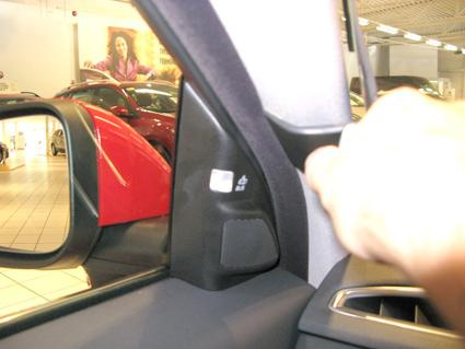 Interiör av en bil med fokus på dörrhandtag och spegel.