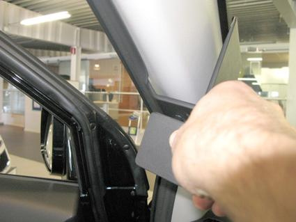 Bild visar en hand som håller i en del av bilens inredning.