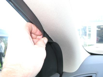 En hand som drar i en tygpanel i en bil.