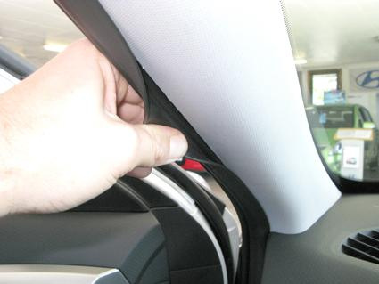 Hand som justerar inredning i en bil, troligtvis en Hyundai Veloster.