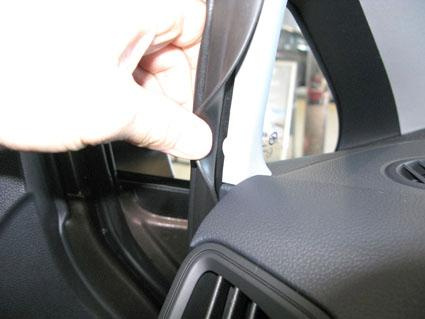 En hand som lyfter på en plastdetalj inuti en bil.