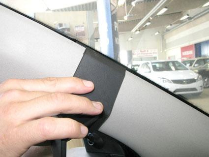 En hand håller i en del av bilens inredning.