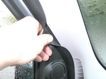 Hand som drar i en gummilist vid en bilruta.