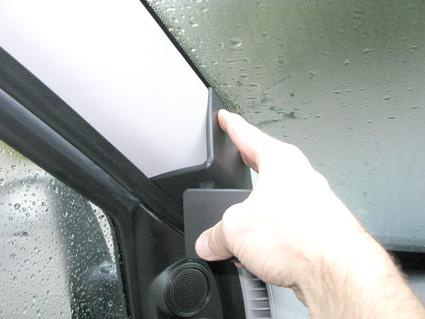 Hand som trycker på en del av bilens interiör, troligtvis runt vindrutan.