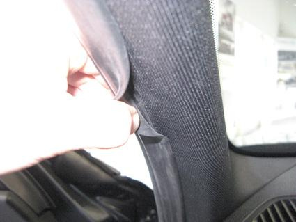 En hand som justerar en tätning vid en bils fönster.