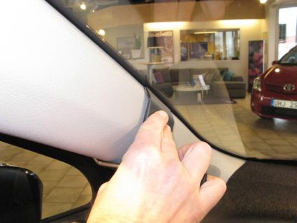 En hand pekar på interiören i en Toyota Yaris, vänster sida.