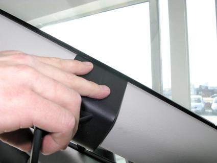 Händer fäster en svart monteringsbygel på inredningen av en bil.