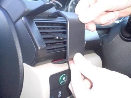 En hand installerar en del på ventilationsgallret i en Honda Accord.