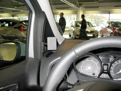 Visar insidan av en bil med fokus på instrumentpanelen och omgivande parkering.