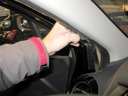 En hand justerar eller tar bort en del i bilen, troligen från en Renault Clio.