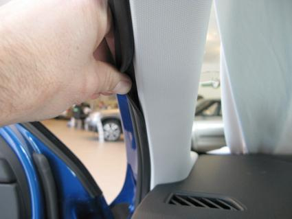 En hand håller i en del av bilens inredning, troligtvis en måltavla för installation.