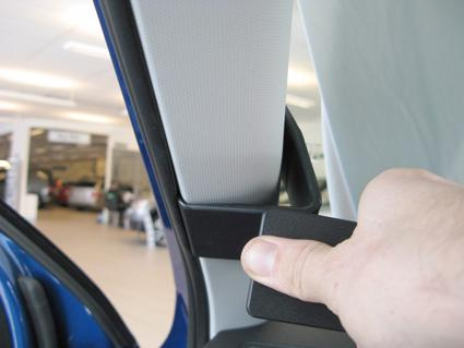 En hand som greppar en del vid dörröppningen i en bil.