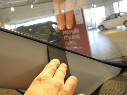 En hand rör vid interiören av en Toyota RAV4, fokus på vänster sida.