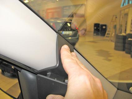 En person pekar på en monteringsbygel i en bil.