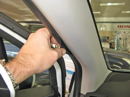 En hand justerar en del vid bilens vänstra sida, troligtvis inuti bilen.