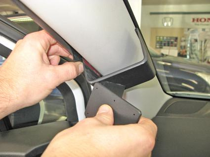 En person monterar en komponent på interiören av en bil.