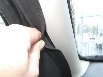 En hand som drar i en svärtad panel i en bil.