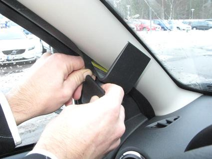 Två händer installerar en monteringsbygel i en bil.