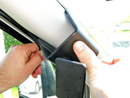 En hand installerar en hållare på en bils inre sida.