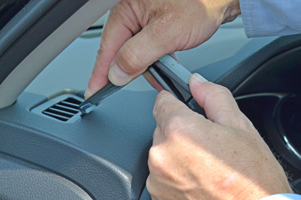 Händer som installerar eller justerar en del i en bildashboard.