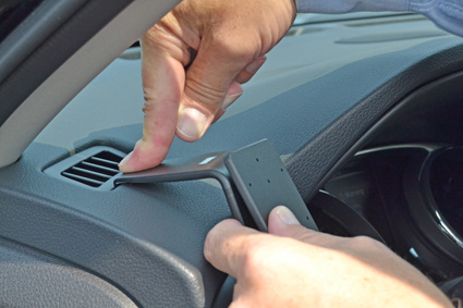 En person installerar en del i en bilinteriör.