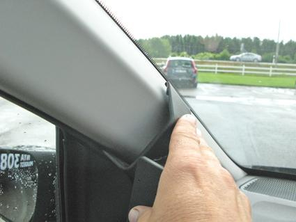 Inre hörn av bilens fönsterram med en hand som pekar.