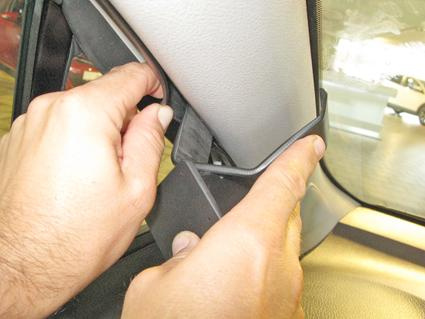 En hand installerar en plastdetalj vid vindrutan i en Toyota Yaris.