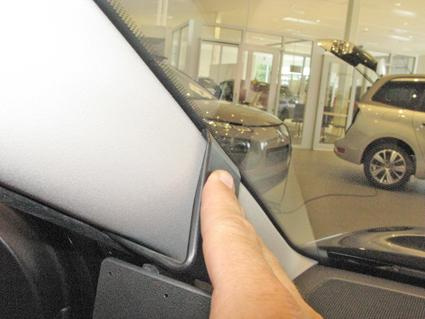 En hand pekar på ett panelområde i en bil.