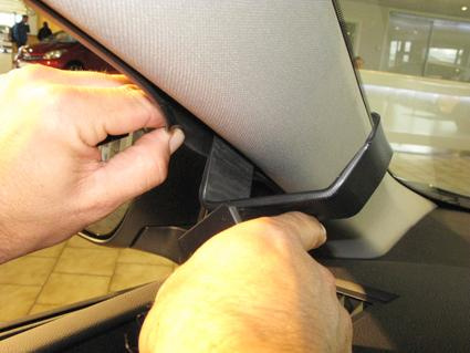 Hand som installerar en komponent vid bilens A-stolpe.