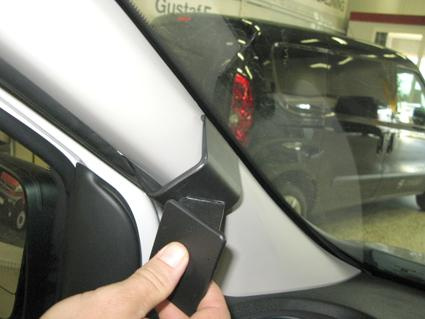 En hand håller en svart del nära bilens vänstra A-stolpe inuti en Renault Trafic.