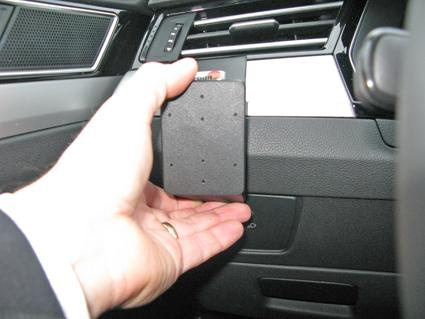 En hand håller en svart enhet vid instrumentpanelen i en Volkswagen Passat.