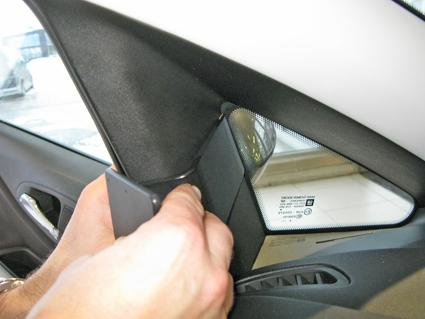 En hand monterar en del vid vänster sida av Opel Corsa.